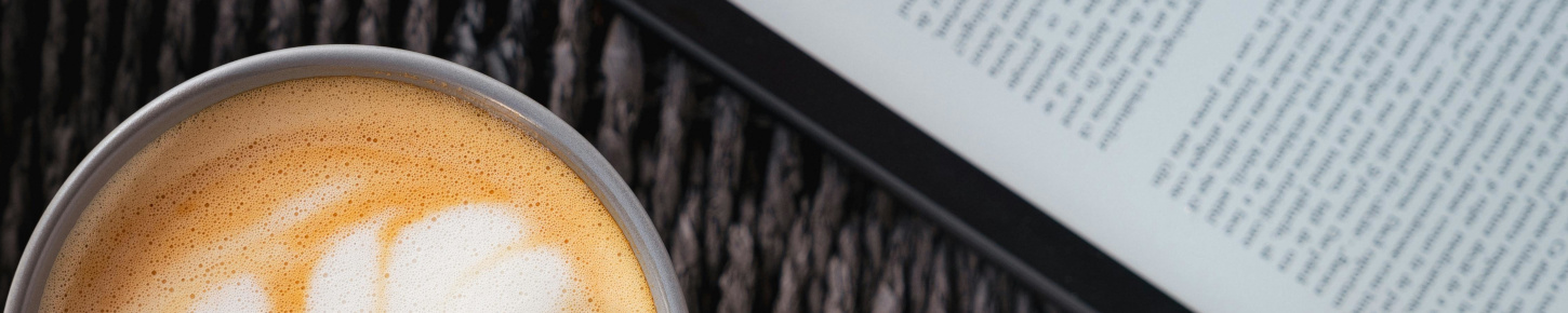 Photo of ereader next to mug of coffee.